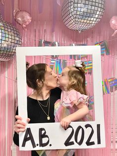 a mother and daughter kissing each other in front of a photo frame that reads ab 2021