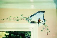 a bird sitting on top of a window sill next to a wall with flowers