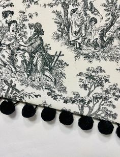 black and white toiler print fabric with pom - poms on it