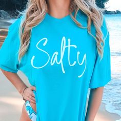 Get ready to dive into coastal vibes with our "Salty Comfort Color Graphic Tee" — the perfect pick for ocean admirers and beach enthusiasts. Designed for those who thrive with sandy toes and the salty sea breeze, our tee embodies the spirit of seaside life. Crafted from high-quality Comfort Color fabric, this graphic short sleeve tee promises exceptional softness and lasting wear. You'll enjoy every sun-soaked moment by the ocean in ultimate comfort. Its chic "Salty" design brings a dash of beac Casual Ocean Color Beach Tops, Casual Ocean Color Tops For Beach, Soft-washed T-shirt For Beach In Spring, Soft-washed T-shirt For Beach Spring Occasion, Blue Surfing T-shirt For Beach Season, Blue Beachy T-shirt For Beach Season, Blue T-shirt For Beach Party, Beachwear Style, Beachy Blue T-shirt For Beach Season, Blue Beachy T-shirt For Beach