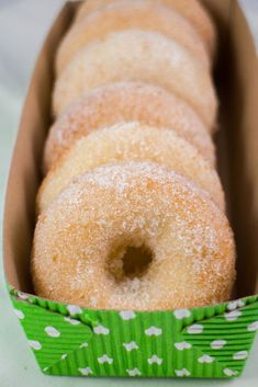 a box filled with donuts sitting on top of a white table next to a green napkin