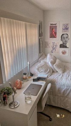 a bedroom with a bed, desk and pictures on the wall next to it's windows