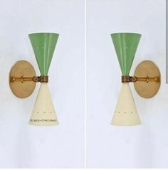 two green and white wall lights mounted to the side of a wall next to each other