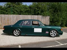 a green car parked in front of a wooden fence