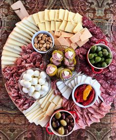 an assortment of cheeses, meats and olives arranged on a platter