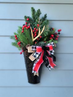 a christmas decoration hanging on the side of a house with antlers and berries in it