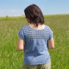 a woman standing in tall grass with her back to the camera