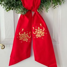 a red bow hanging on the front door with gold decorations and greenery around it