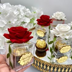 there are three small boxes with chocolates and roses in them on the table next to each other