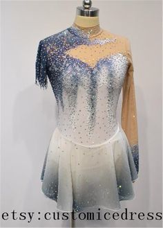 a white and blue dress with silver sequins on the top, in front of a white wall