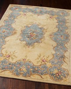 a large rug with blue and yellow flowers on it's center, sitting on a wooden floor