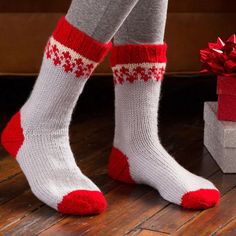 a woman's legs with red and white socks next to a gift box on the floor