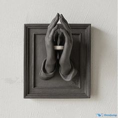 a pair of hands are wrapped in a scarf on a square wall mounted object with a black frame