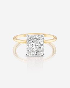 an engagement ring with a square cut diamond in the center and two tone gold band