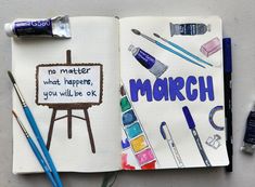 an open notebook with markers, paint and watercolors on it that says march