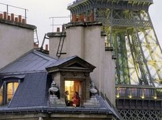 two people are standing on the roof of a building with a view of the eiffel tower