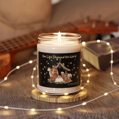 a lit candle sitting on top of a wooden table next to a string of lights