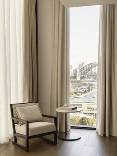 a chair and table in front of a window overlooking the sydney harbour bridge, australia