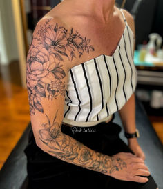 a woman sitting on top of a counter with tattoos on her arm and shoulder,