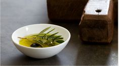 a white bowl filled with olive oil next to a wooden block