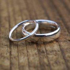 two silver rings sitting on top of a wooden table