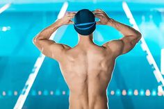 a man standing in front of a swimming pool holding his hat up to his head