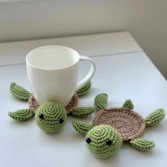 two crocheted sea turtle coasters and a coffee cup on a white table