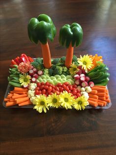 a platter filled with vegetables and fruit on top of a wooden table in the shape of palm trees