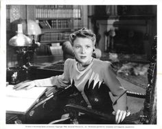 an old black and white photo of a woman sitting at a desk