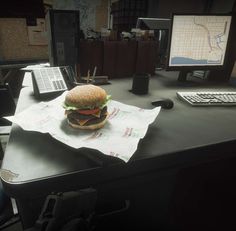 a hamburger sitting on top of a desk next to a computer