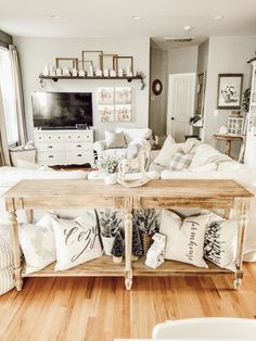 a living room filled with furniture and pillows on top of a wooden table in front of a window