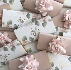 pink flowers are on top of white cards with gold lettering and monogrammed envelopes