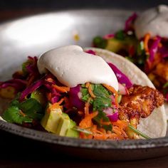 two tacos with meat, lettuce and carrots in a metal bowl