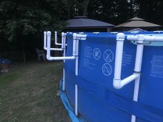 a blue swimming pool with white piping and umbrellas in the backgroud