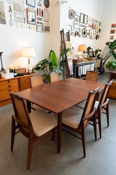 a dining table and chairs in a room with pictures on the wall