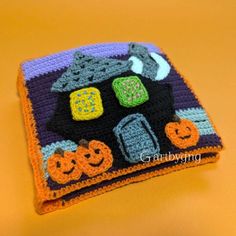 two crocheted halloween coasters sitting on top of a yellow table with pumpkins