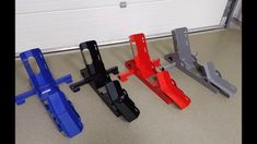 four different colored metal parts sitting on the floor in front of a garage door,