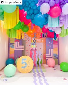 balloons and streamers are hanging from the ceiling in front of a birthday party backdrop