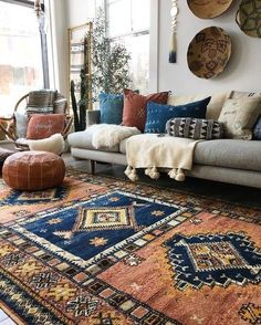 a living room filled with lots of furniture and pillows on top of a blue rug