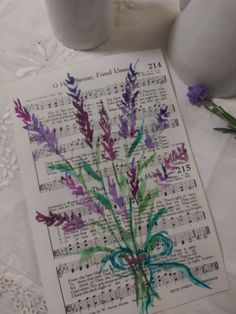 an old sheet with some flowers on it and music sheets next to it in front of two white vases