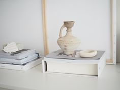 a white vase sitting on top of a table next to some books and other items