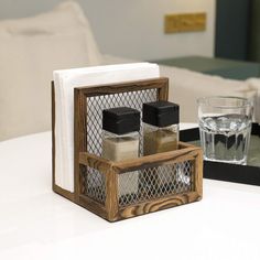 a wooden holder with spices and salt sits on a table next to a glass of water