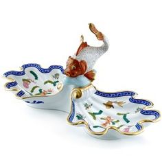 a figurine is sitting on top of a white plate with blue and gold trim