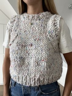 a woman wearing a white knitted sweater with multicolored buttons on the back