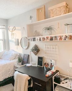 a bedroom with a bed, desk and pictures on the wall above it in front of a window