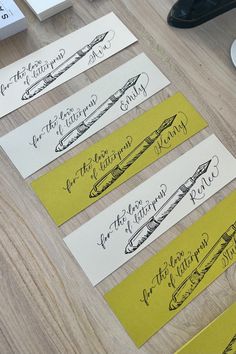 four handwritten name tags sitting on top of a wooden table next to a keyboard