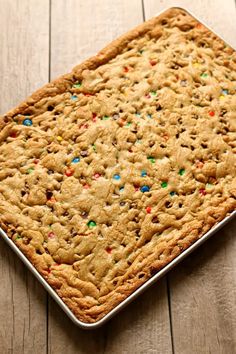 a cookie cake with sprinkles and chocolate chips on a baking sheet, ready to be eaten