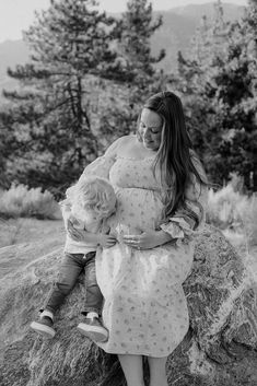 a woman holding a child on top of a rock