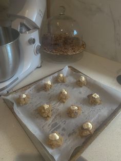 doughnuts are on a baking sheet in front of a mixer and glass bowl