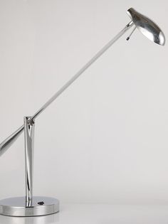 a silver desk lamp on a white surface with one arm extended and the other arm down